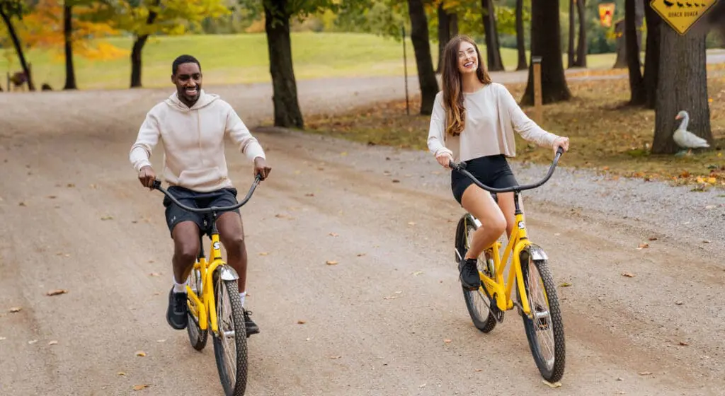 a couple riding yellow bikes on a dirt road