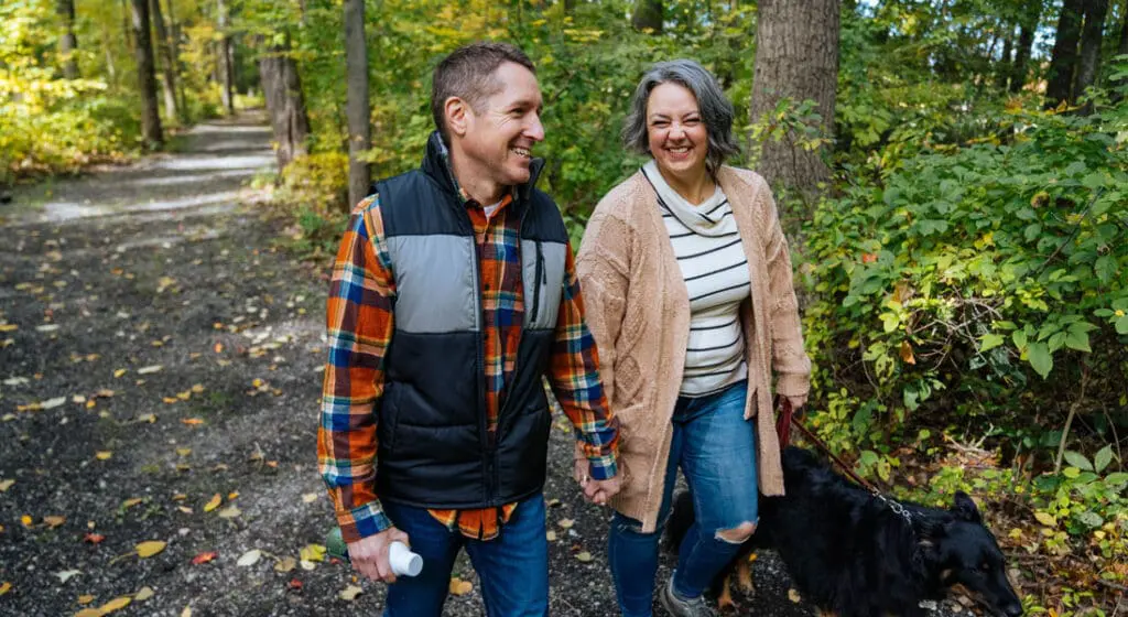 man and woman holding hands on a trail in the woods