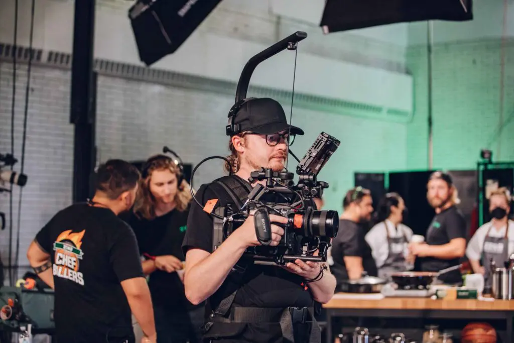 A professional video production camera and crew on a commercial set, representing the high-quality equipment used by JV Studios.