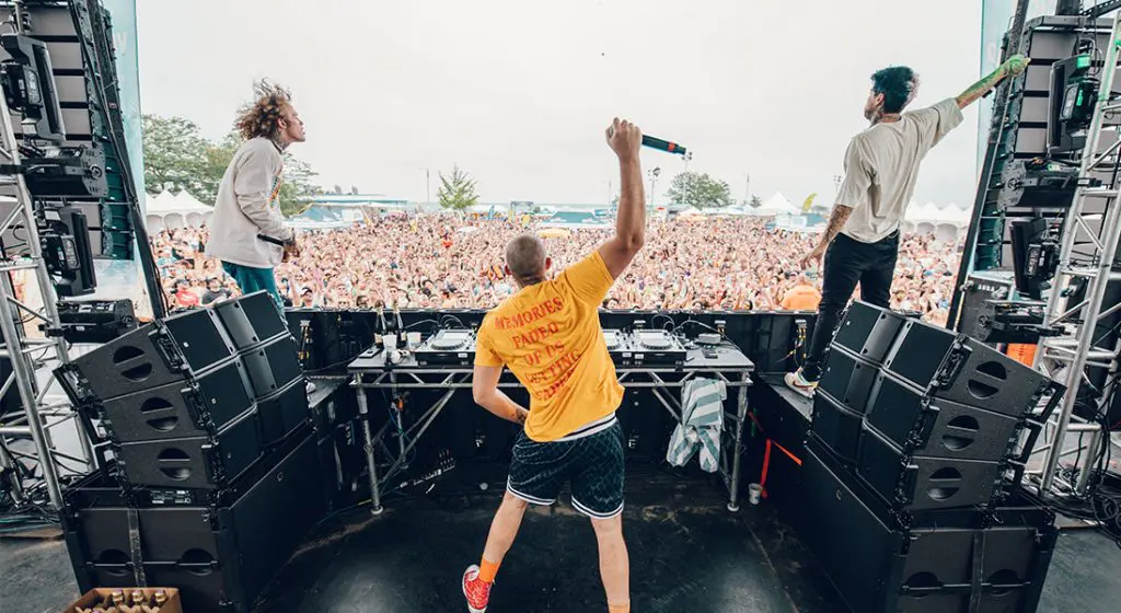 back of dj on stage looking at the crowd at a music festival