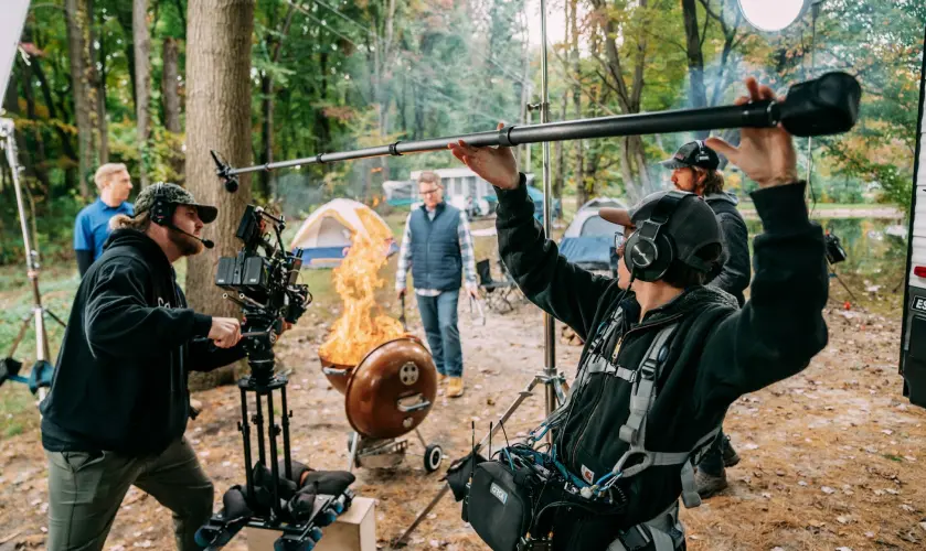 behind the scenes photo of man holding a boom mic during a video shoot