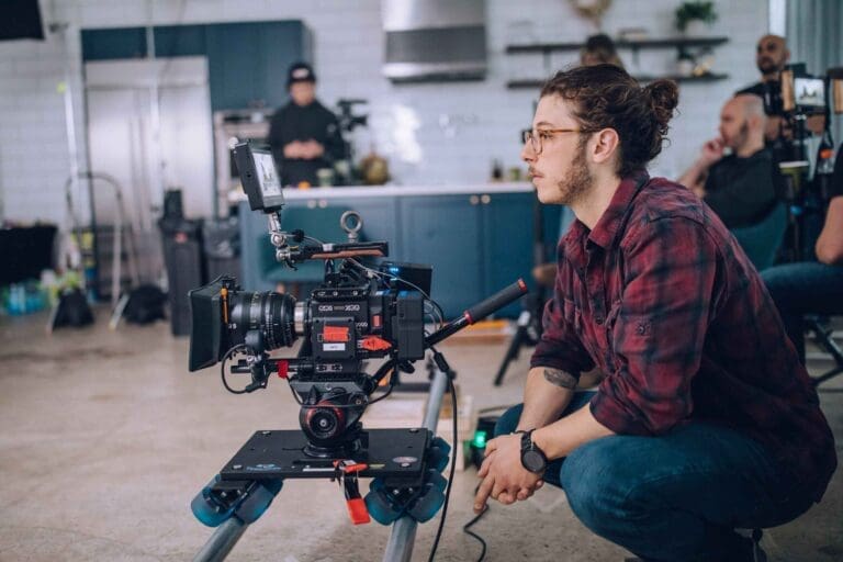 man in red shirt kneeling while looking into a camera on a commercial shoot