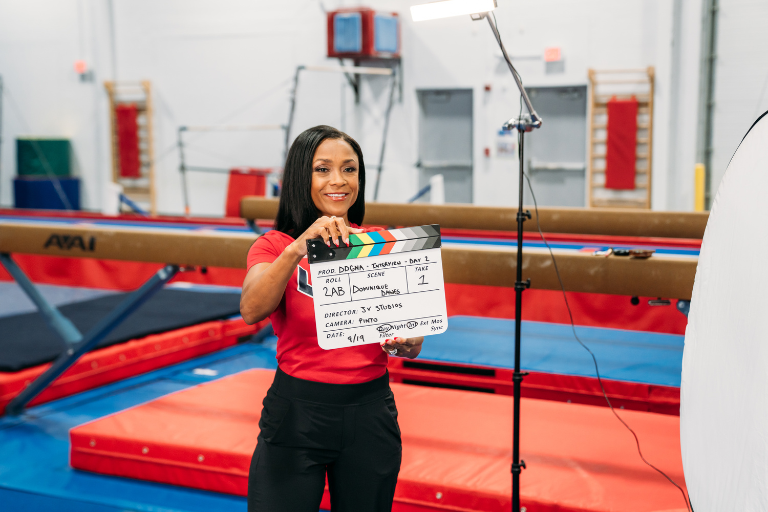 Dominque Dawes holds production board for video shoot in her gym